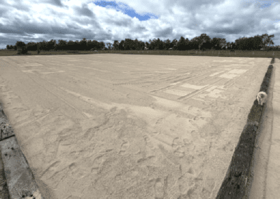 Large flat sandy area with construction vehicles in the distance and cloudy sky